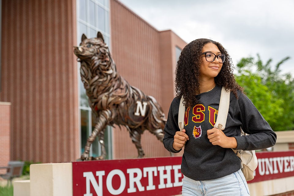 Student standing by Northern State University wolf statue