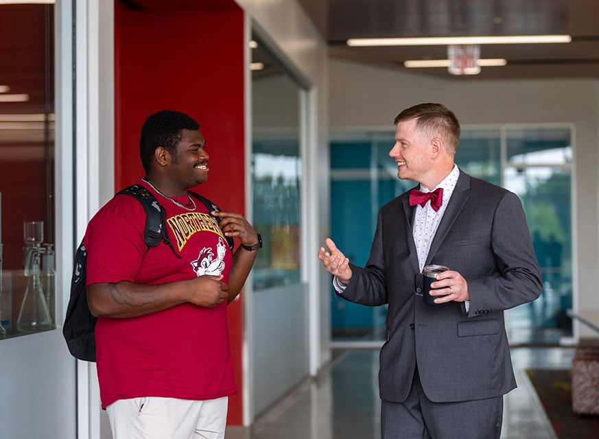 Student talking with faculty member in modern campus building